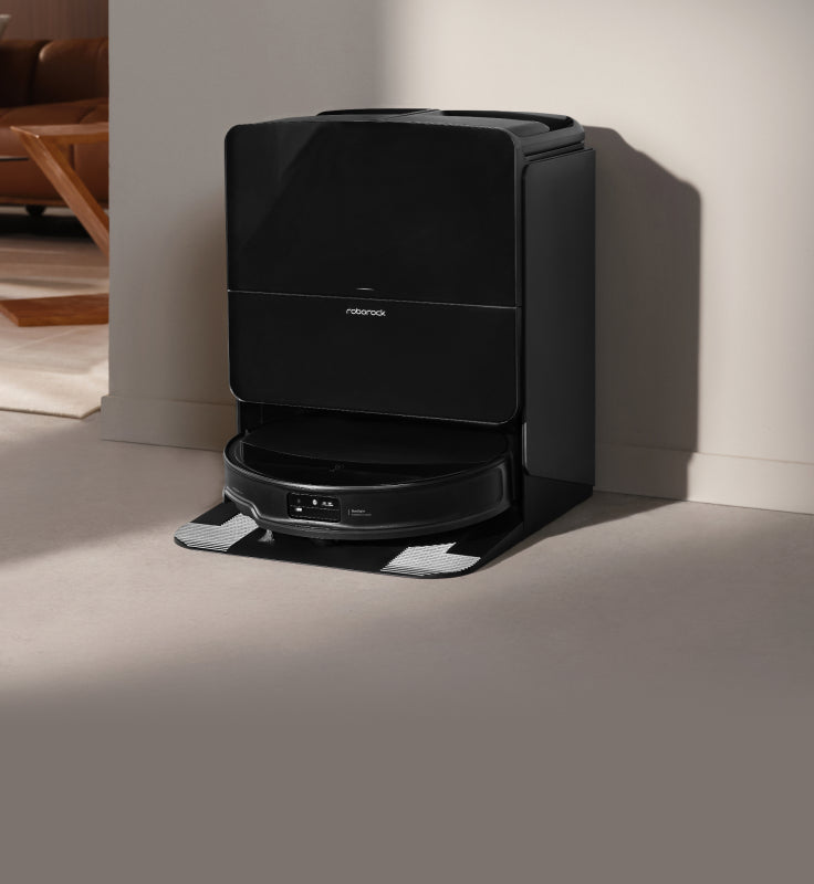 Black Roborock Saros 10R robot vacuum docked in a black base station on a light-colored floor